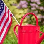 Red watering can with American flag in garden setting | Great Garden Activities You Can Do Over Memorial Day Weekend | memorial day garden