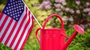 Red watering can with American flag in garden setting | Great Garden Activities You Can Do Over Memorial Day Weekend | memorial day garden