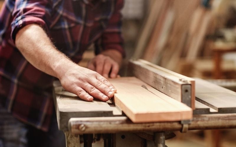 cropped image hands skilled craftsman cutting wooden plank | How To Build Your Own Wood Arbor For Your Fall Garden