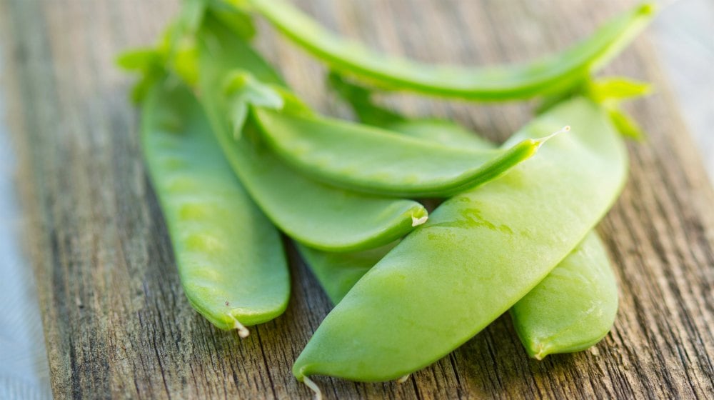 freshly picked snow peas on a rustic board | Spring Vegetable Garden Plants Perfect For Spring Growing Season | vegetable garden plants | vegetables to plant in spring