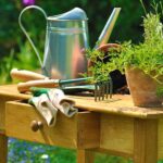 gardening tools and plants arranged on a wooden table in the garden | Awesome Potting Bench Ideas You Can DIY | garden work bench | featured