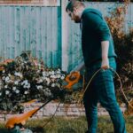 Man Holding Orange Electric Grass Cutter On Lawn | Common Gardening Mistakes And Tips On How To Avoid Them | Featured