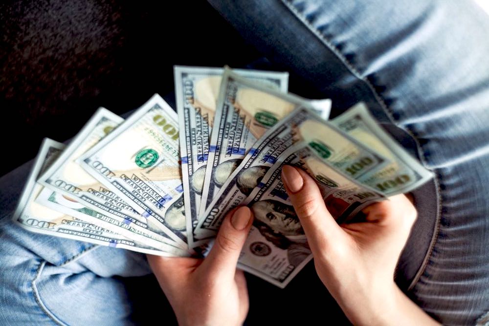 woman hands holding dollars | Pros And Cons Of Square Foot Gardening | Garden Season